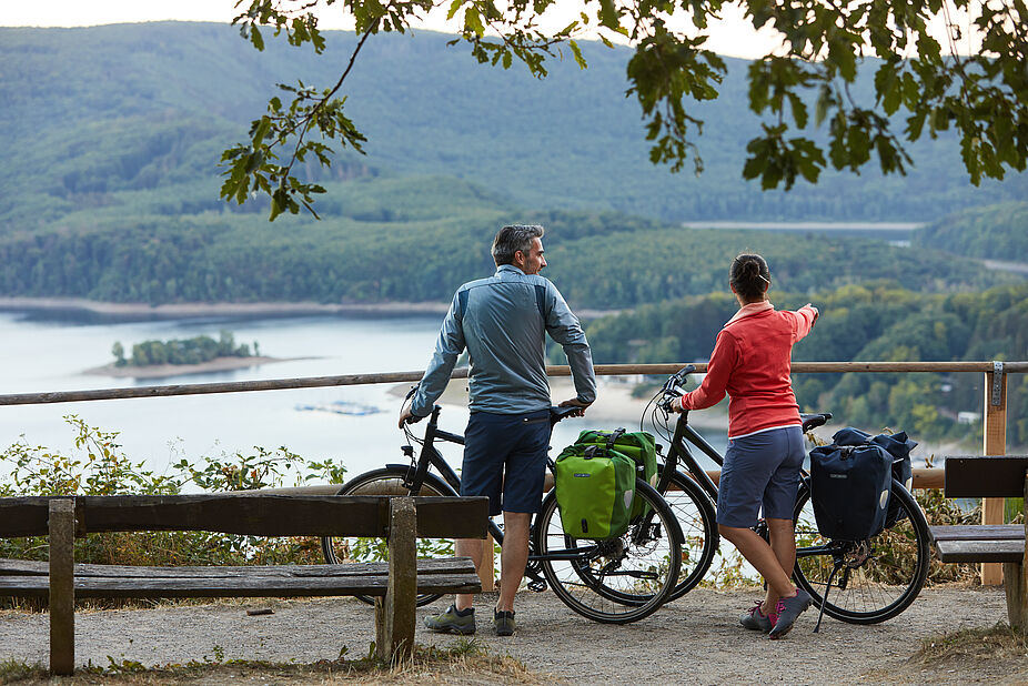 Radreisen Zwei Personen mit Fahrrad an einer Bank